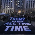 La gente despliega un cartel en el que se lee en inglés "Trump miente todo el tiempo" al otro lado de la calle del edificio de la Corte Penal de Nueva York, poco después de la acusación del ex presidente Donald J. Tump, en Nueva York (EE.UU.). EFE/ Justin Lane