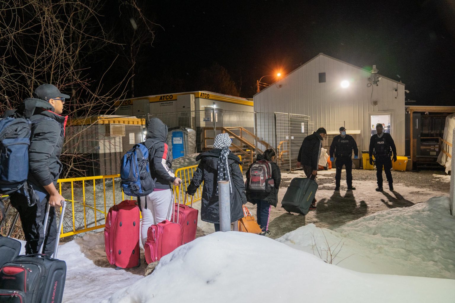 Dos agentes de la policía reciben a un grupo de inmigrantes procedentes de Nueva York en la frontera de Roxham Roada que separa EE.UU. de Canadá en Plattsburgh, Nueva York. EFE/Ángel Colmenares