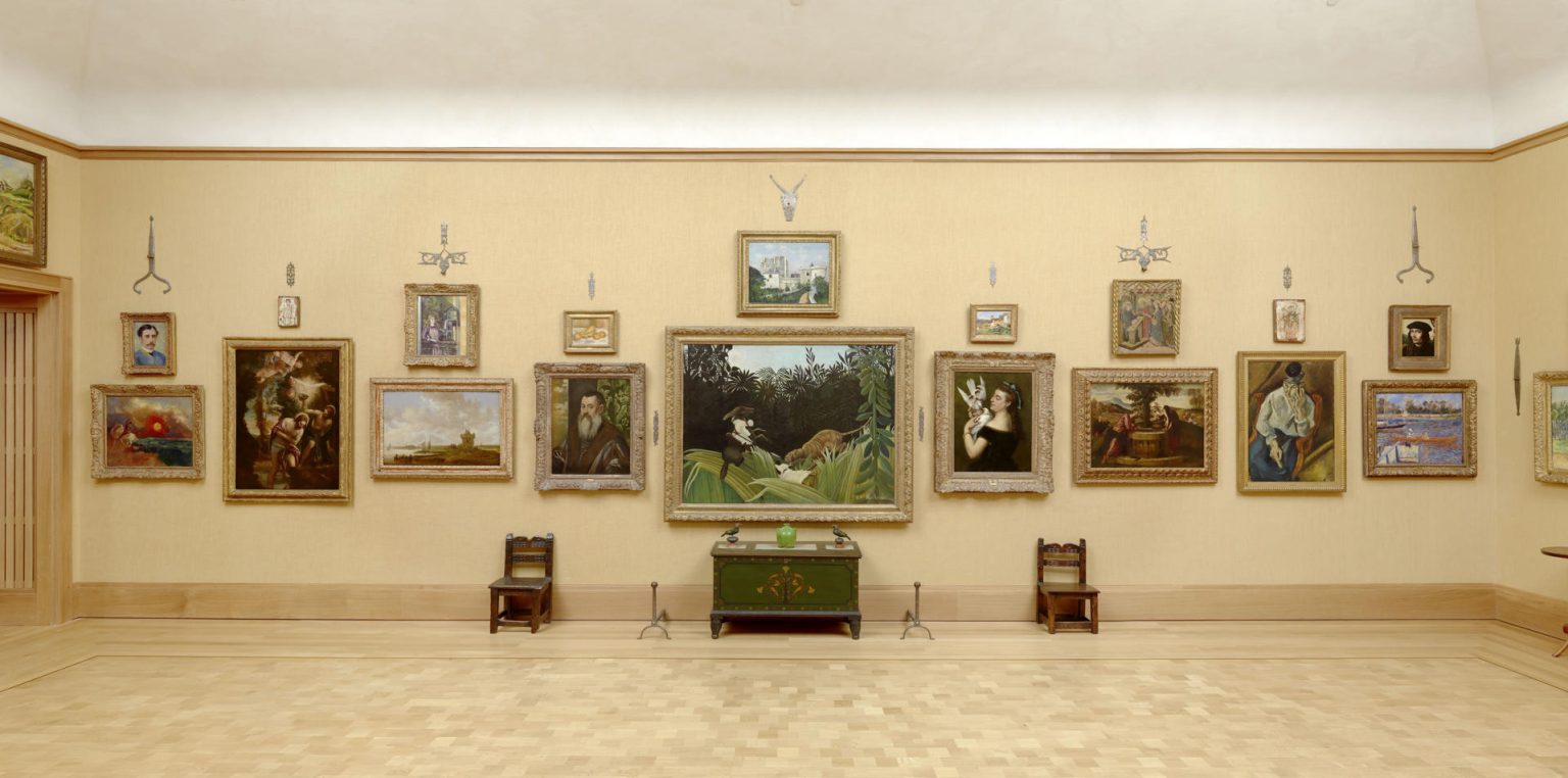 Fotografía cedida por la Fundación Barnes donde se aprecia "Room 14" (Sala 14) con una pared con varios cuadros como "Exploradores atacados por un tigre" de Rousseau en el centro, "Mujer con paloma" de Courbet a su derecha y "Retrato de un caballero" de Tintoretto a su izquierda, o las obras más alejadas en cada extremo de la pared, "San Jorge y el dragón" de Redon a la izquierda y "El Sena en Argenteuil" de Renoir a la derecha, expuestos dentro de la sede de la fundación ubicada en la avenida de Benjamin Franklin en Filadelfia, Pensilvania (EE.UU.). EFE/ The Barnes Foundation