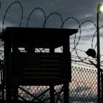 Fotografía de archivo que muestra la silueta de un miembro de la Fuerza de Tarea Conjunta (i) subiendo a una garita junto a un alambrado en un perímetro de seguridad en Campo Delta, estación naval en Guantánamo (Cuba). EFE/JOHN RILEY