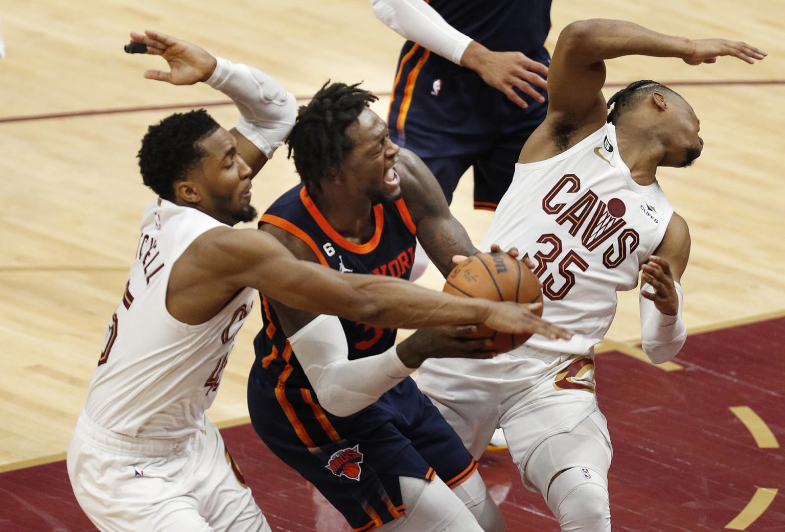 El alero de los Knicks, Julius Randle (c), comete una falta ofensiva entre el guardia de los Cavaliers, Donovan Mitchell (i), y el guardia de los Cavaliers, Isaac Okoro (d), durante la segunda mitad del juego 1 de los playoffs de la primera ronda de la Conferencia Este de la NBA entre los Cleveland Cavaliers y los New York Knicks, hoy, en el Rocket Mortgage Fieldhouse en la ciudad de Cleveland, Ohio (Estados Unidos). EFE/ David Maxwell