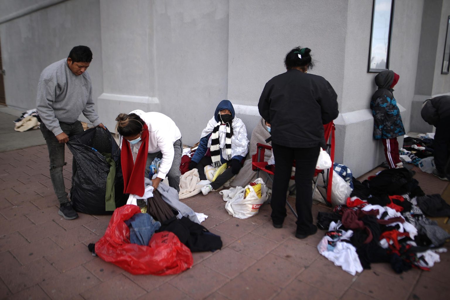 Inmigrantes indocumentados que recién cruzaron la frontera desde México buscan ropa de su talla en bolsas de ropa donada por voluntarios y organizaciones. Imagen de archivo. EFE/Jesús Rosales