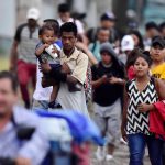 Un padre que carga a su hijo camina junto a la caravana migrante, rumbo a la frontera guatemalteca de Agua Caliente, a su paso por San Pedro Sula (Honduras). Imagen de archivo. EFE/José Valle