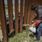 Repartidores de comida rápida entregan pedidos a migrantes en el muro fronterizo hoy, en la ciudad de Tijuana, Baja California (México). EFE/Joebeth Terríquez