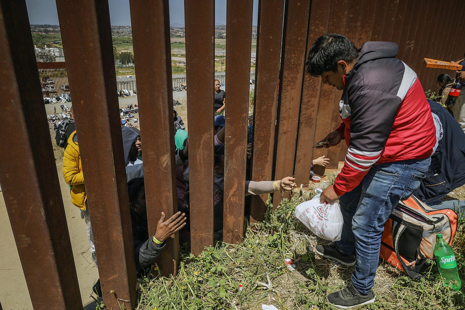 Repartidores de comida rápida entregan pedidos a migrantes en el muro fronterizo hoy, en la ciudad de Tijuana, Baja California (México). EFE/Joebeth Terríquez