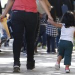 Familias migrantes cruzan la calle después de ser procesados en la estación central de autobuses antes de ser llevados a Caridades Católicas en McAllen, Texas (EE.UU.). EFE/LARRY W. SMITH