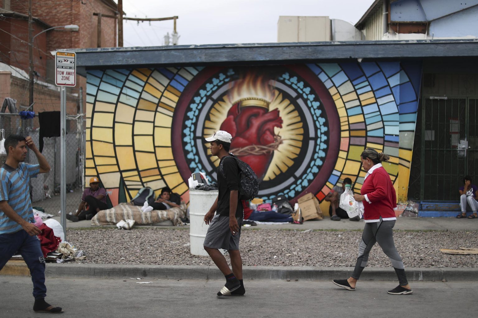 Migrantes caminan y otros duermen a la intemperie, el miércoles 3 de mayo de 2023, en un acampado para migrantes que cruzan desde México establecido en los alrededores de la iglesia Sagrado Corazón, en el área central de la ciudad fronteriza de El Paso, Texas (EE.UU.). EFE/ Jesús Rosales