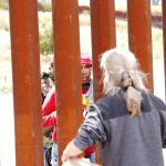 Un hombre habla con padres de familias que se quedaron al otro lado de la valla fronteriza que separa EE.UU. de México, hoy, en San Diego, California (EE.UU.). EFE/ Manuel Ocaño