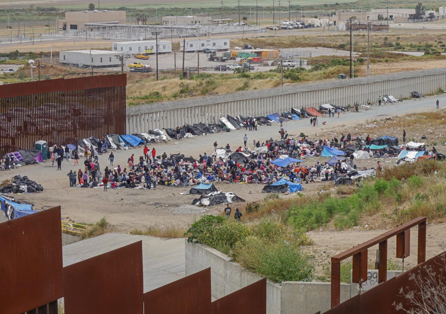 Vista general donde se observa a migrantes en un campamento junto al muro fronterizo hoy en Tijuana, Baja California (México). La frontera norte de México se mantuvo en tranquilidad este viernes, pese a que se auguraba el caos en el primer día sin el Título 42 de Estados Unidos con decenas de miles de migrantes que esperarían cruzar pese a las nuevas restricciones estadounidenses.  EFE/Joebeth Terriquez