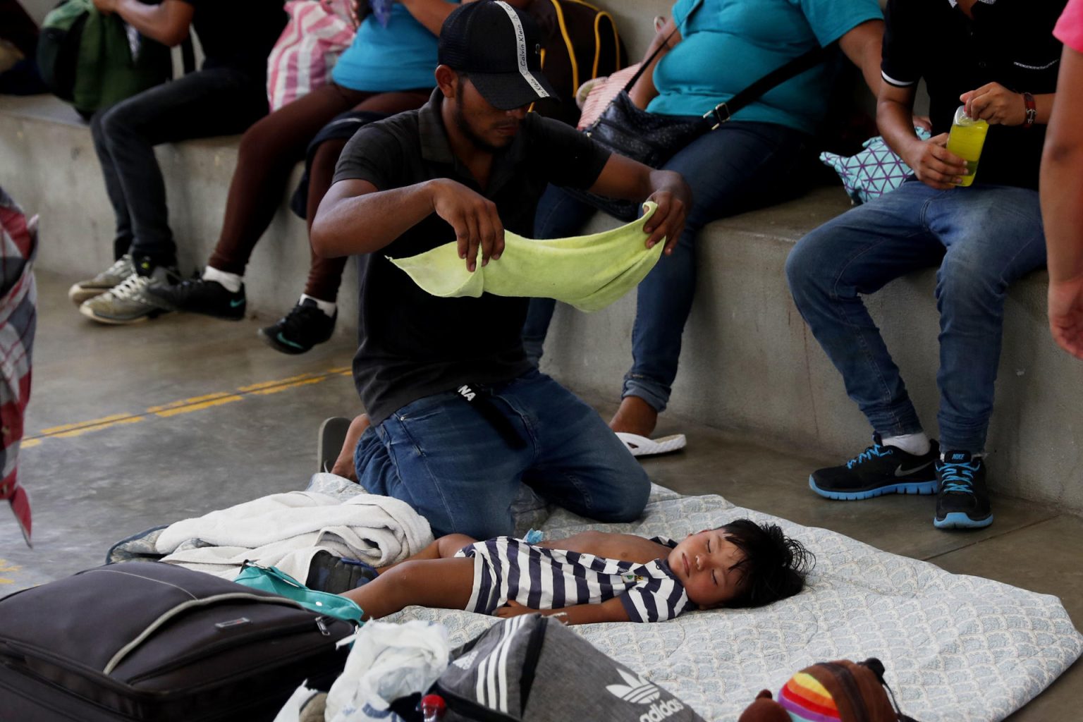 Fotografía de archivo donde aparece un migrante hondureño mientras trata de refrescar a su hijo después de varias horas caminando en carretera bajo el sol. Imagen de archivo. EFE/Esteban Biba