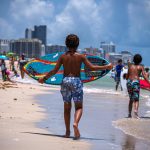 Un niño juega con una tabla de surf en una playa de Miami Beach, Florida. Fotografía de archivo. EFE/Giorgio Viera