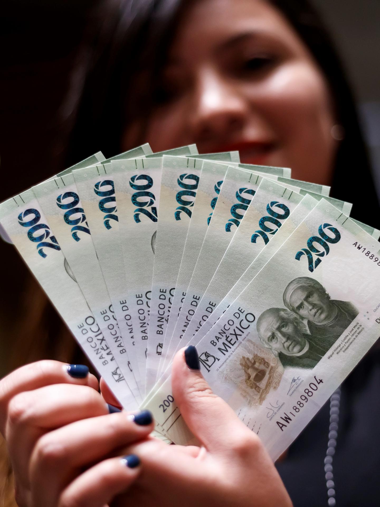 Fotografía de archivo de una mujer muestra billetes de 200 pesos en Ciudad de México (México). EFE/ José Méndez