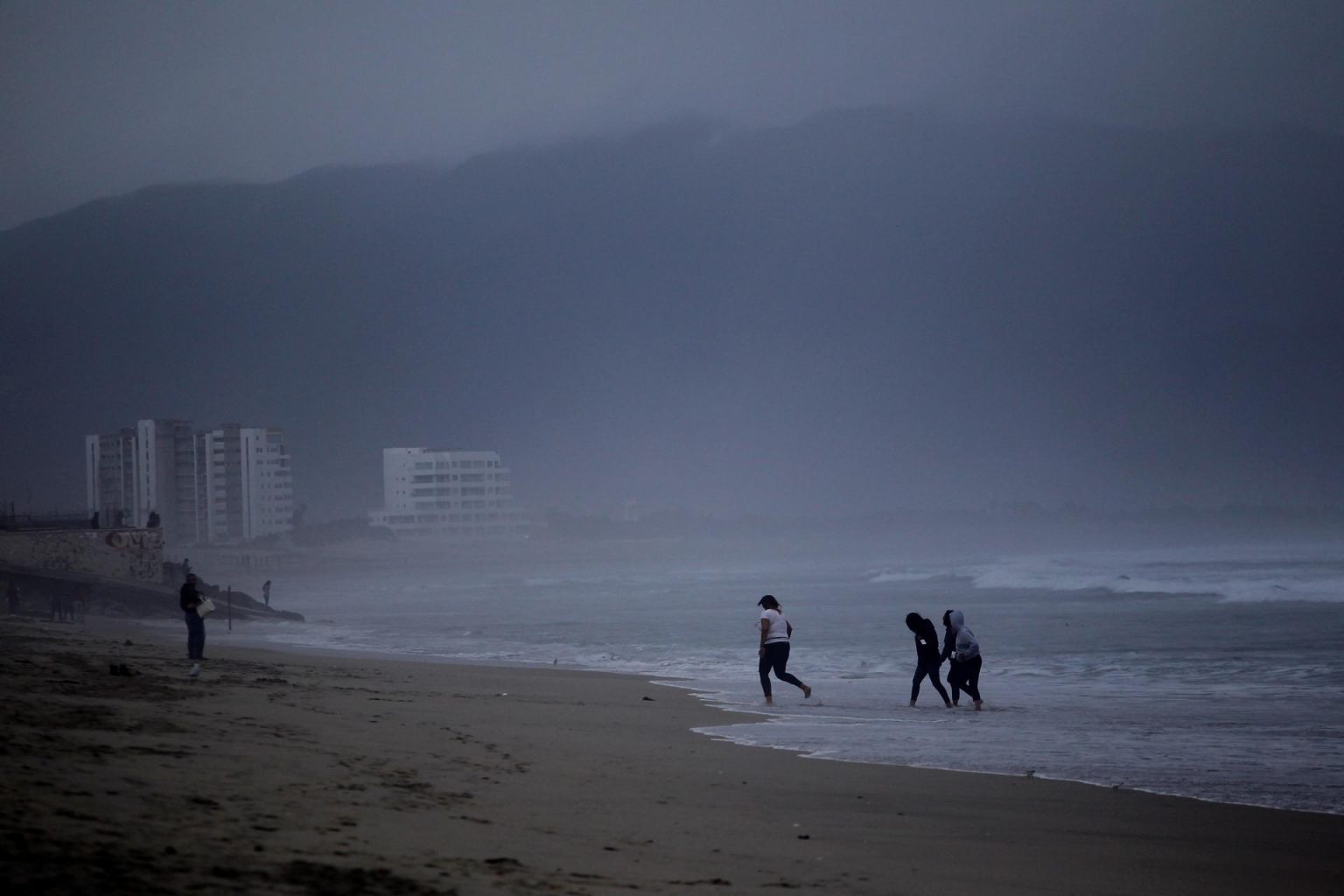 Personas juegan en la playa durante una tormenta, en una fotografía de archivo. EFE/ Alejandro Zepeda