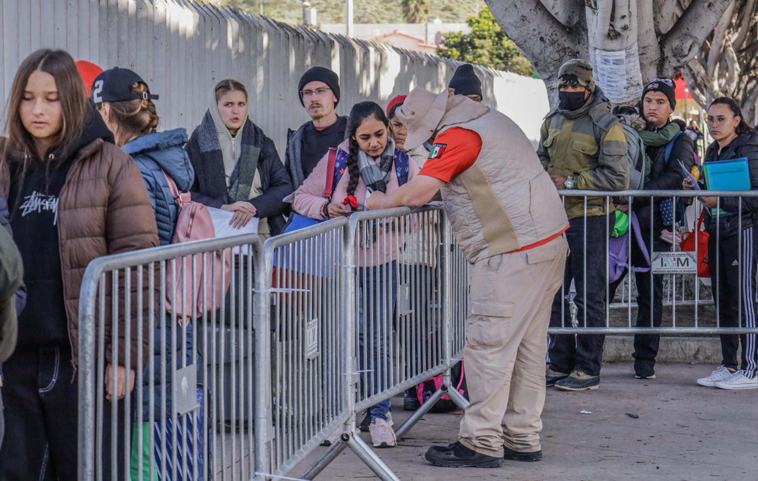 Integrantes del Instituto Nacional de Migración (INM), orientan a migrantes en el puerto fronterizo de San Ysidro, en la ciudad de Tijuana (México). Imagen de archivo. EFE/Joebeth Terríquez