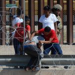 Migrantes cruzan las alambradas con filosas cuchilas colocadas en los muros hoy para entregarse a las autoridades y pedir asilo en Ciudad Juárez, Chihuahua (México). EFE/Luis Torres