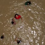 Personas se bañan en el agua del río Bravo, hoy, en Ciudad Juárez (México). EFE/ Luis Torres