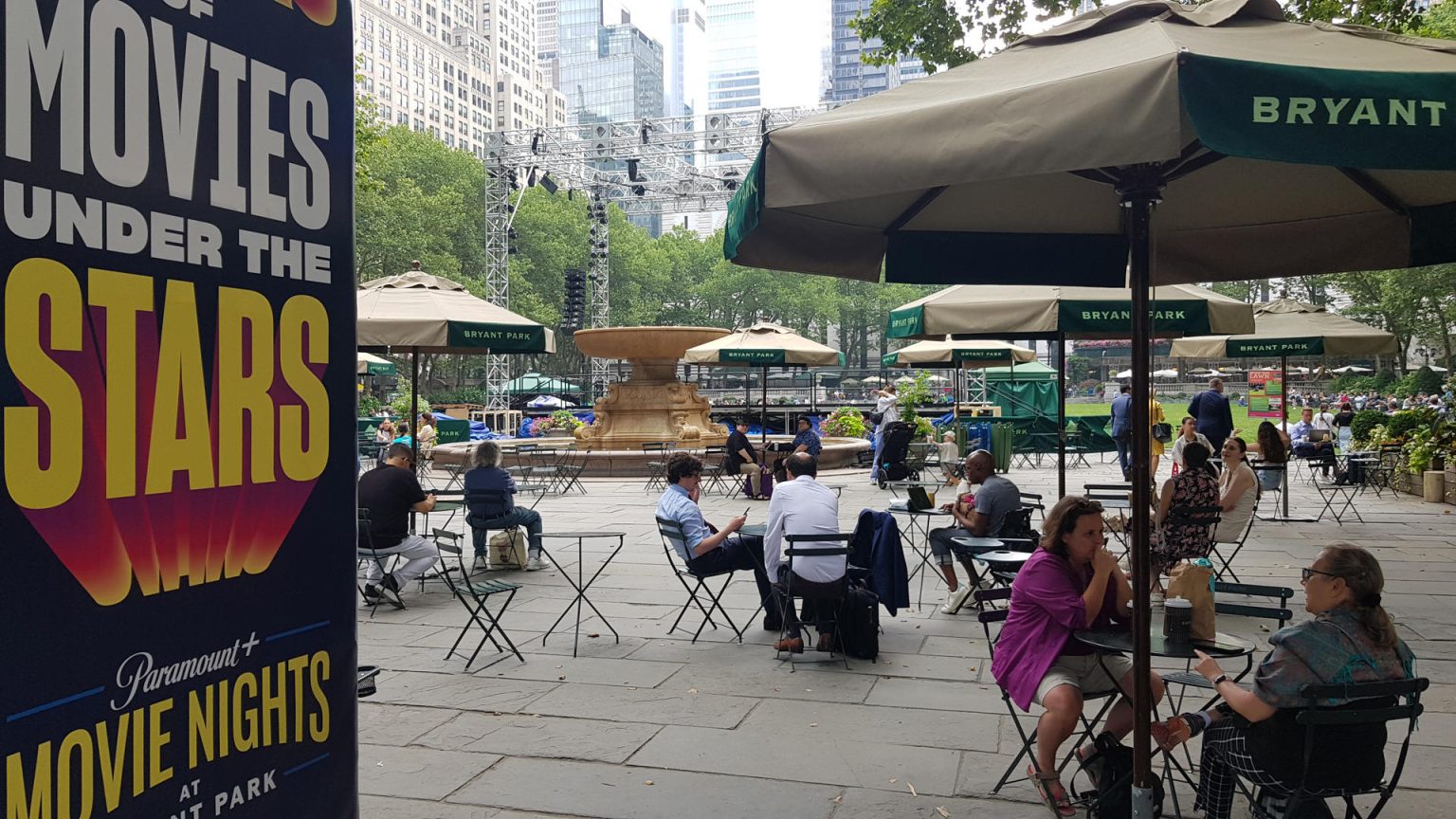 Unas personas descansan junto a un cartel del ciclo "Movies under the stars" (Películas bajo las estrellas), que ofrece proyecciones de películas al aire libre, el 29 de junio de 2023, en el Parque Bryan en Nueva York (EE.UU.). EFE/ Jorge Fuentelsaz