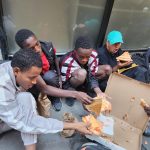 Inmigrantes comen pizza donada mientras hacen fila en espera de ser enviados a un albergue y con la esperanza de tener pronto un empleo en Nueva York (EE.UU.). Fotografía de archivo. EFE/ Ruth Hernández Beltran