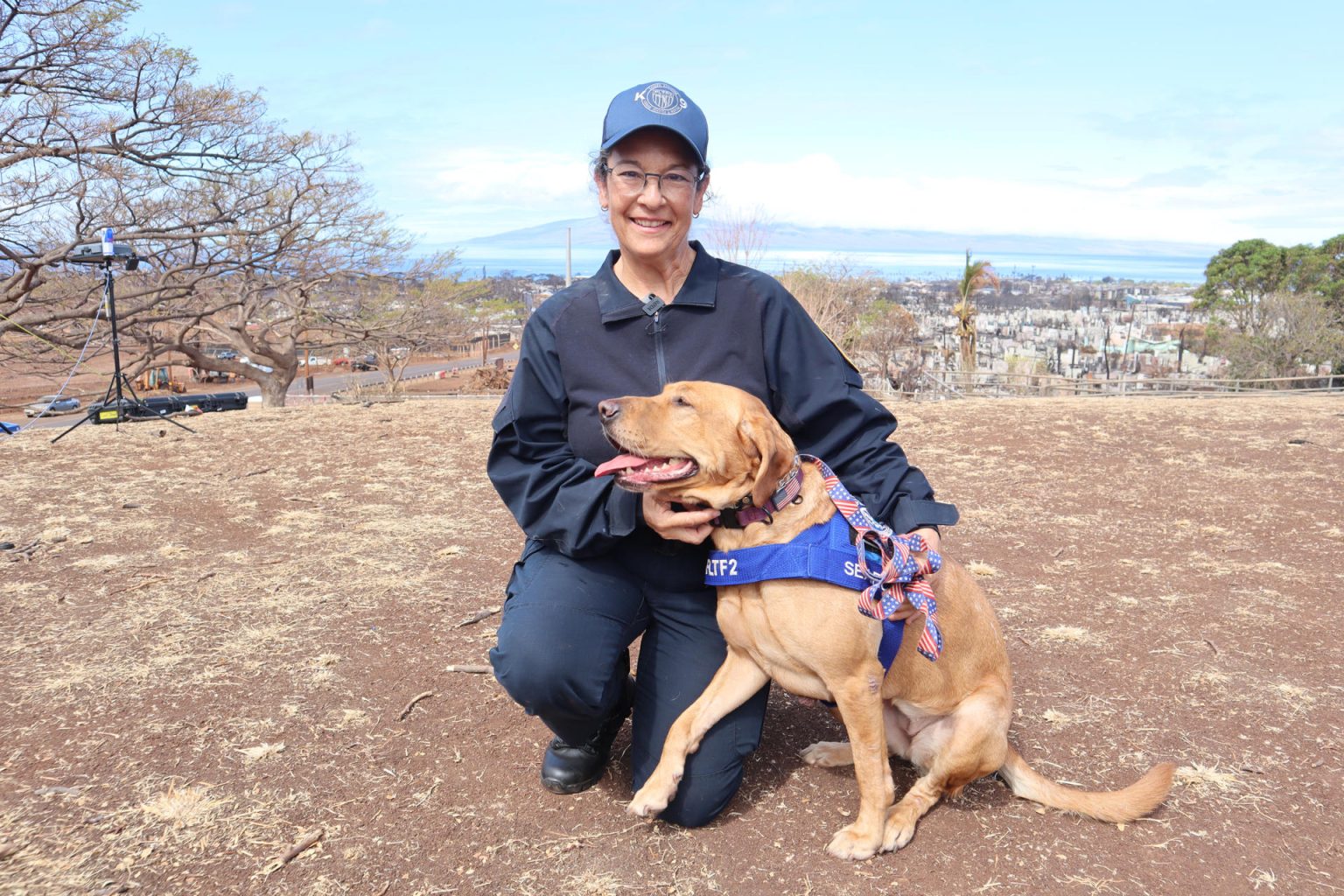 La entrenadora Sylvia Arango posa junto a Freya, una golden retriever de cuatro años y medio, especialista en búsqueda y rescate de personas, el 21 de agosto de 2023, en Lahaina (EE.UU.). EFE/Octavio Guzmán