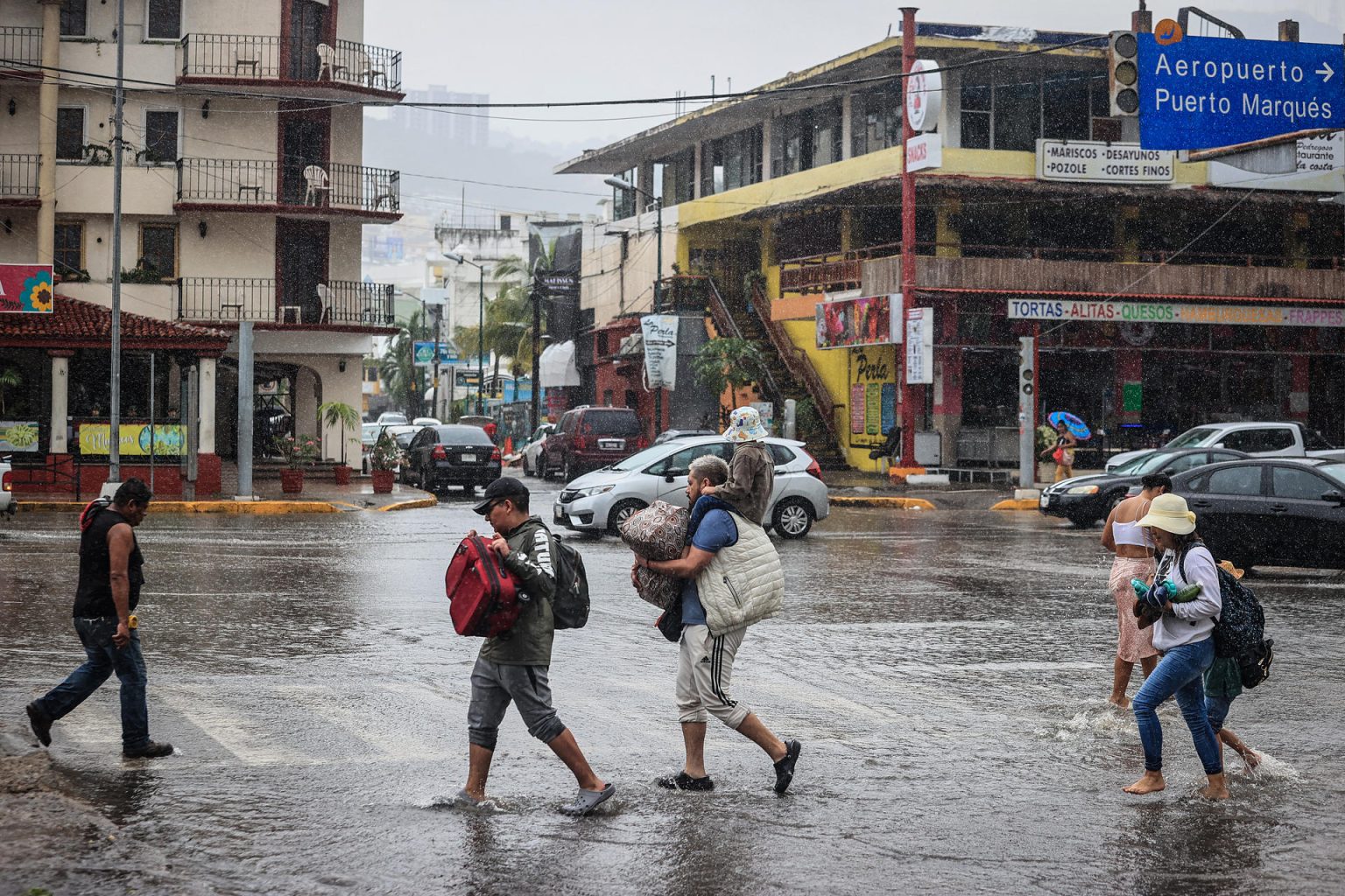 Personas caminan por una calle encharcada debido a las fuertes lluvias en el balneario de Acapulco, estado de Guerrero (México). EFE/David Guzmán