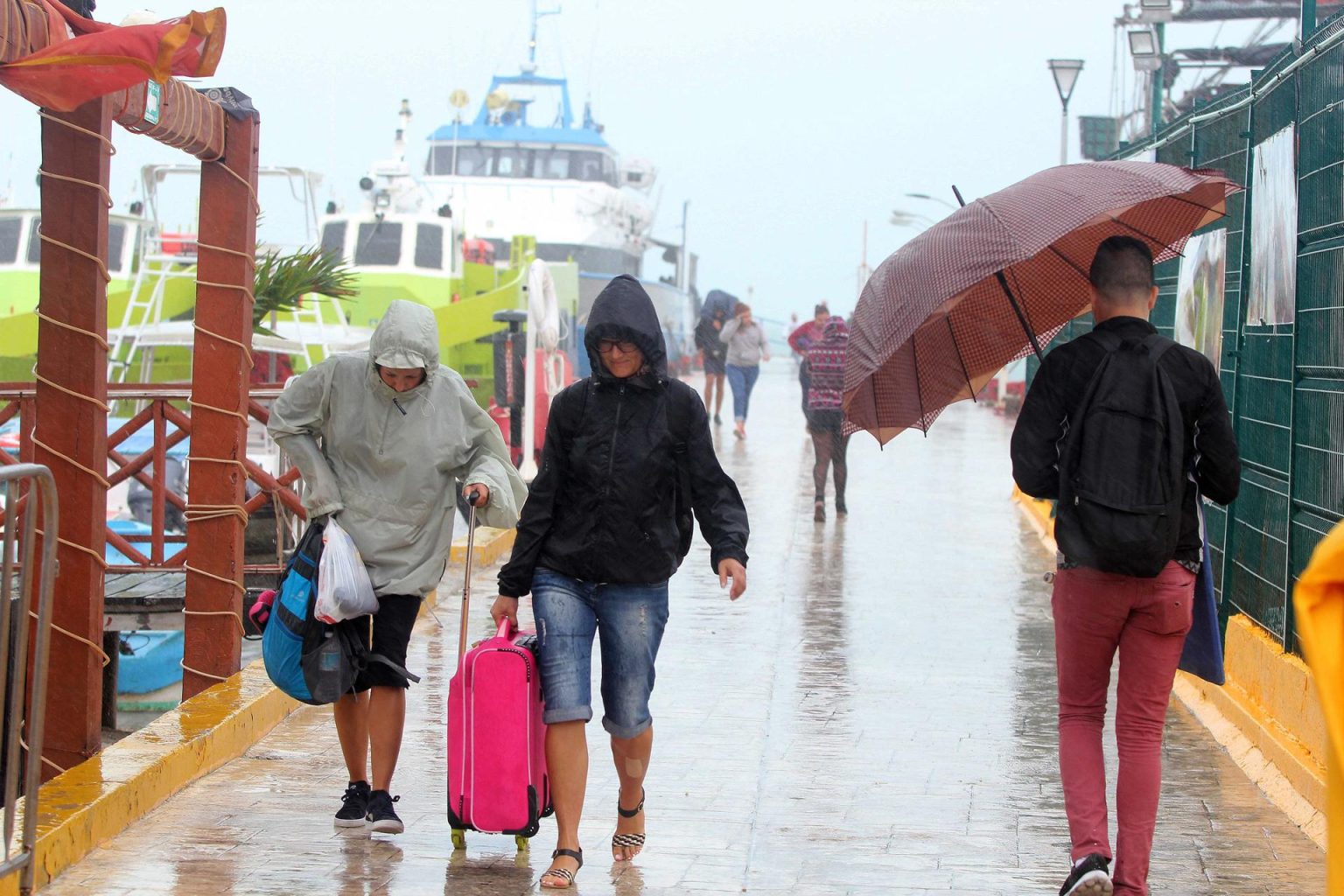 Fotografía de archivo de turistas caminando bajo la lluvia en las playas de Cancún en el estado de Quintana Roo (México). EFE/Alonso Cupul