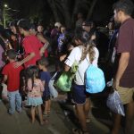 Familias de migrantes suben en la madrugada de hoy a un bus en la ciudad de Danlí, al oriente de Honduras. EFE/Gustavo Amador