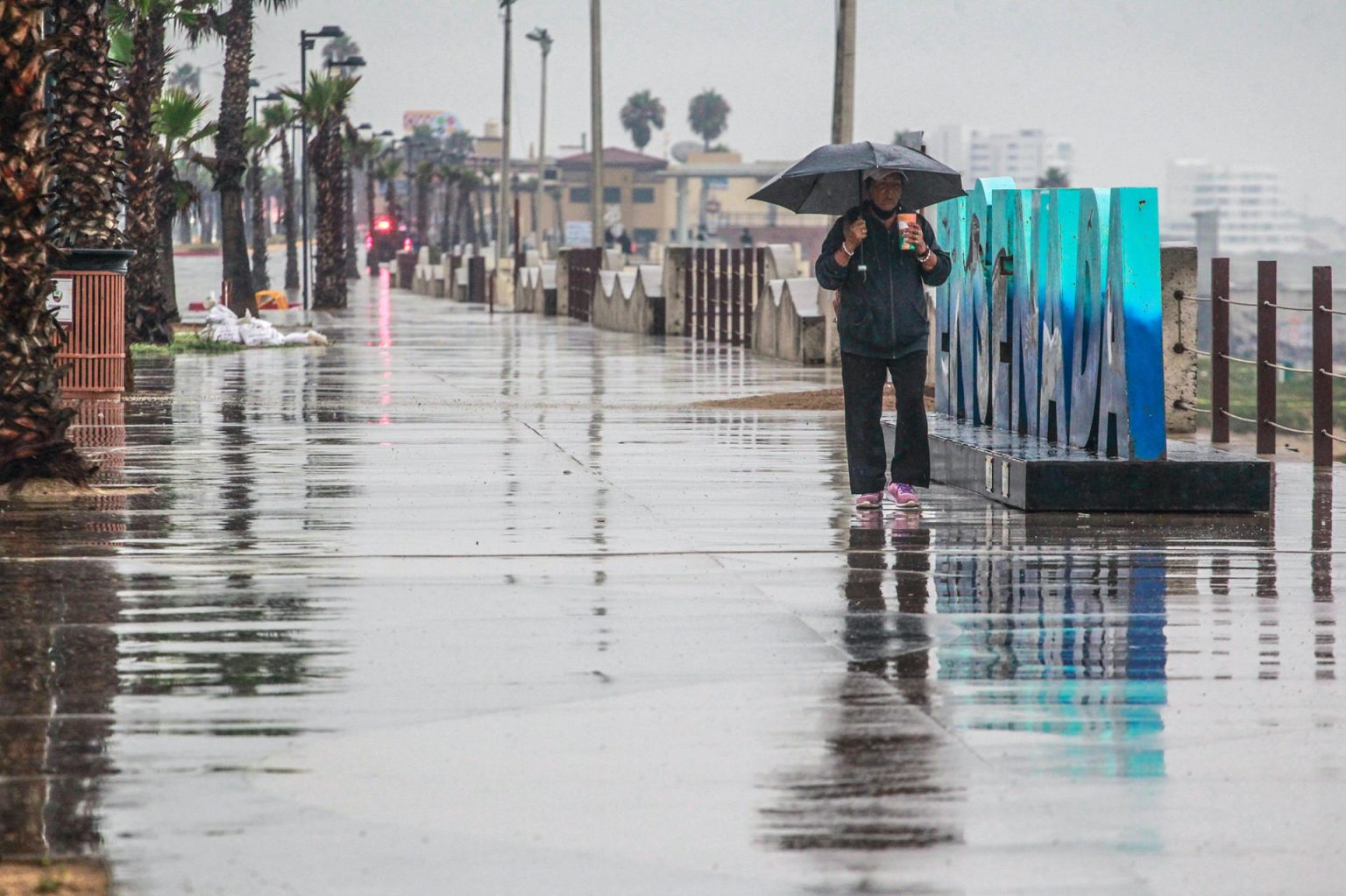 Una persona camina bajo la lluvia hoy, en el puerto de Ensenada en Baja California (México). EFE/Alejandro Zepeda