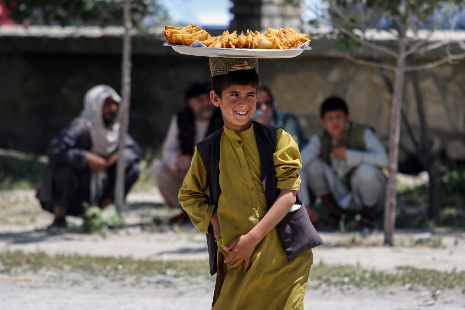 Un niño afgano vende bocadillos en una carretera en vísperas del segundo aniversario de la toma de posesión del gobierno en Kabul, Afganistán. EFE/SAMIULLAH POPAL