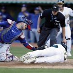 JJ Bleday (d - abajo), de los Atléticos de Oakland, fue registrado este lunes, 7 de agosto, al barrerse sobre el plato para anotar una carrera, ante la mirada del receptor de los Rangers de Texas, Mitch Garver (i), y del juez Adam Beck (c), durante un partido de la MLB, en el estadio Alameda County, en Oakland (California, EE.UU.). EFE/John G. Mabanglo