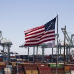 Una bandera de EE. UU. sobre barcos de conetenedores en Los Angeles, California, en una fotografía de archivo. EFE/EPA/Etiene Laurent