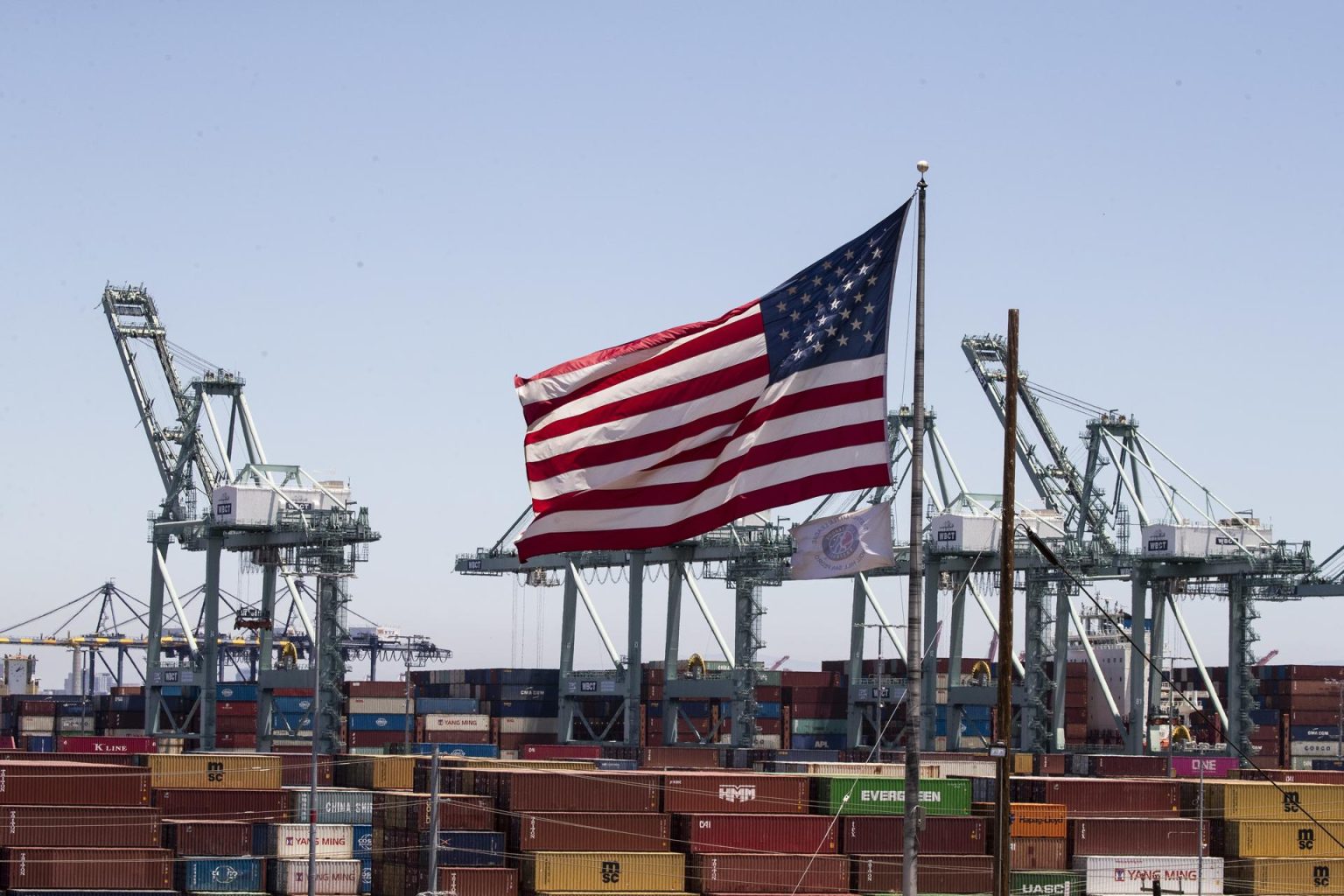 Una bandera de EE. UU. sobre barcos de conetenedores en Los Angeles, California, en una fotografía de archivo. EFE/EPA/Etiene Laurent