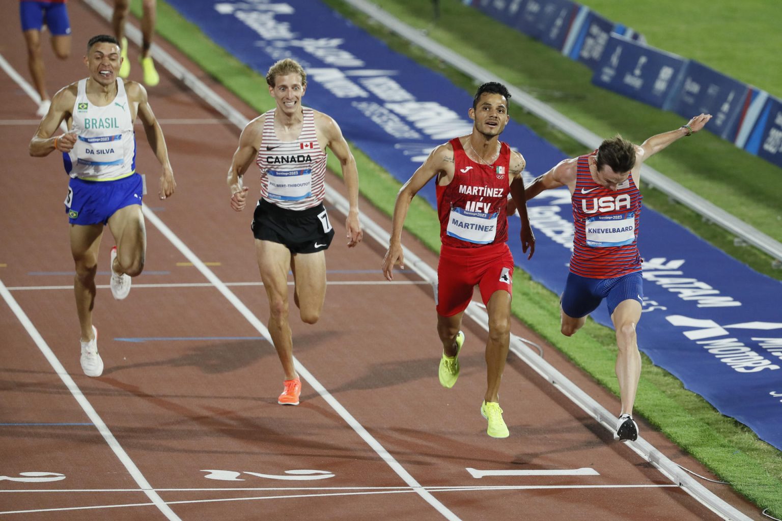 El estadounidense Kasey Knevelbaard (d) fue registrado este martes, 31 de octubre, al ganar la medalla de oro de la prueba masculina de los 5.000 metros planos del Atletismo de los Juegos Panamericanos 2023, en Santiago de Chile. EFE/Carlos Ortega