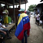 William Maldonado, un migrante venezolano de 22 años sostiene una bandera de Venezuela en una estación de recepción migratoria. EFE/ Bienvenido Velasco