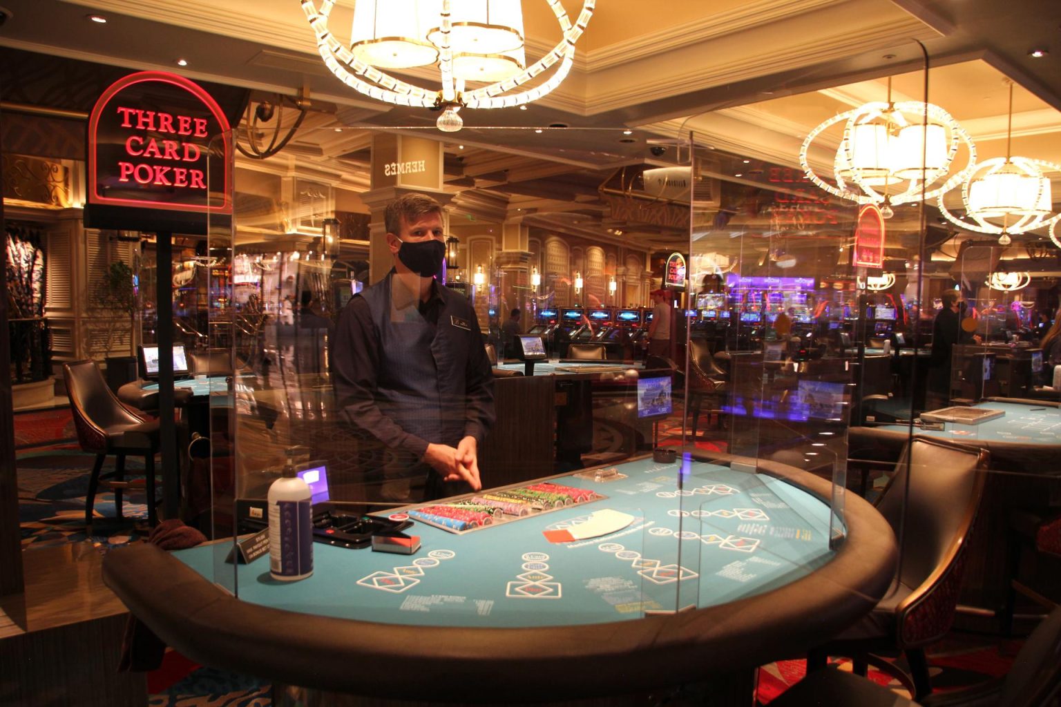 Un empleado del hotel Bellagio viste tapabocas y espera junto a una mesa de póquer con divisiones de cristal en Las Vegas, Nevada. EFE/Adriana Arévalo