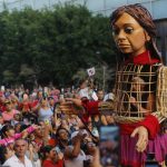 La marioneta Amal, que representa a una niña migrante siria, recorre hoy entre miles de personas el centro histórico de la ciudad de Guadalajara, Jalisco (México). EFE/ Francisco Guasco