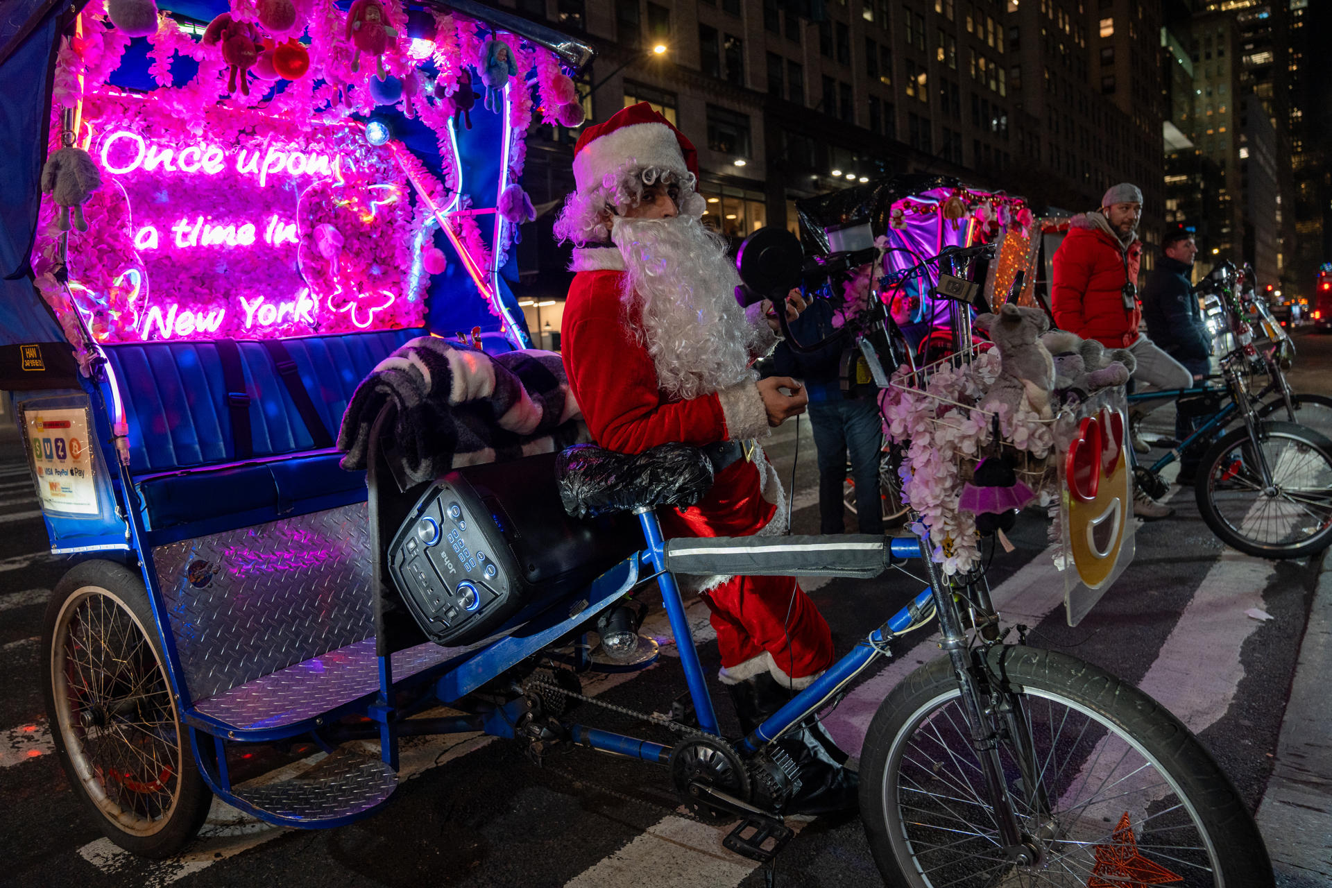 Una persona disfrazada de Papá Noel espera clientes para su bicitaxi frente a la plaza de Bryant Park, el15 diciembre de 2023, en Nueva York (EE.UU.). EFE/ Angel Colmenares
