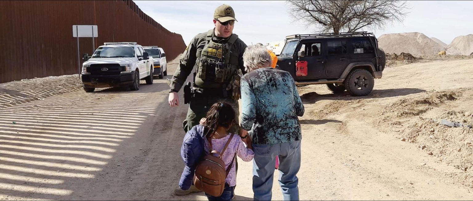 Fotograma cedido por Love Project Films donde aparece la budista judía, de 82 años, Shura Wallin, cofundadora del grupo humanitario Samaritanos de Green Valley, mientras lleva de la mano a una niña de 5 años, la cual viaja sola, para entregarla a un agente de la Patrulla Fronteriza en la frontera de Arizona, durante una escena del documental 'Shura' que se estrenará oficialmente en marzo 2024 durante el festival The American Documentary and Animation Film en Palm Springs, California (EE.UU.). EFE/Love Project Films /SOLO USO EDITORIAL /NO VENTAS /SOLO DISPONIBLE PARA ILUSTRAR LA NOTICIA QUE ACOMPAÑA /CRÉDITO OBLIGATORIO