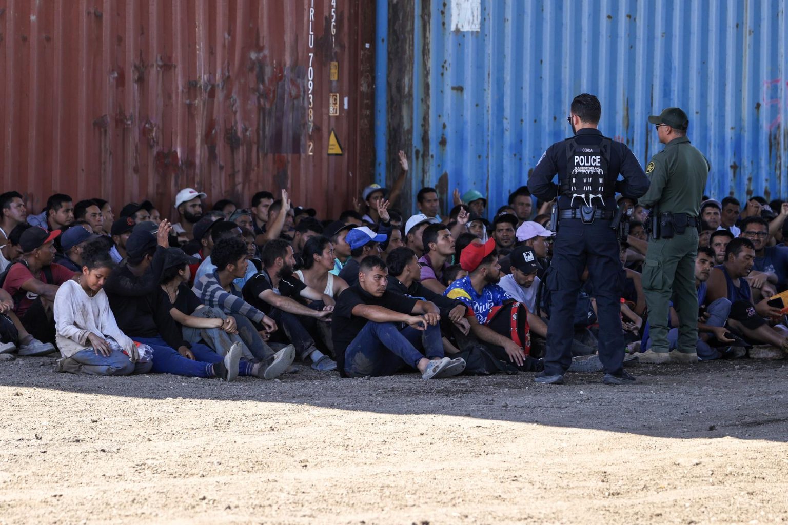 Un oficial de la policía de Aduanas de Estados Unidos (i) y un oficial de la Patrulla Fronteriza (d) reúnen a migrantes en Shelby Park, en Eagle Pass, Texas (EE.UU.), en una fotografía de archivo. EFE/Adam Davis