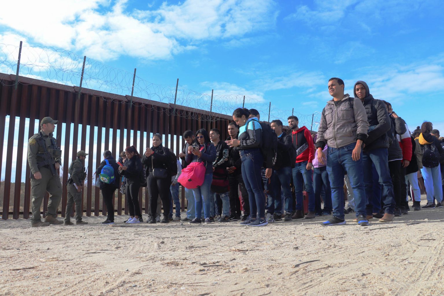 Unos agentes de la Patrulla Fronteriza estadounidense mantienen en filas organizadas a un grupo de migrantes el 29 de noviembre en el puesto fronterizo de Jacumba, a unas 75 millas (120 kilómetros) al este de San Diego, California (EEUU). EFE/Manuel Ocaño