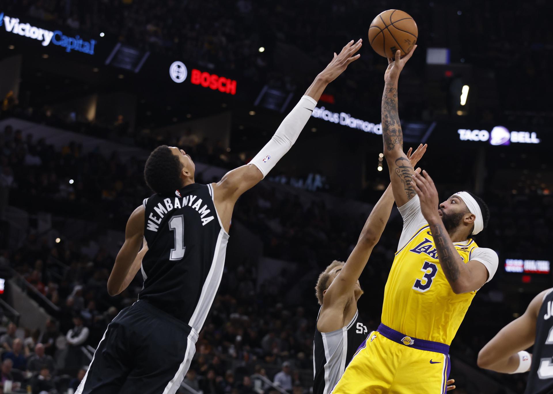 El delantero de Los Angeles Lakers, Anthony Davis (d), dispara sobre el centro de San Antonio Spurs, Victor Wembanyama, de Francia (i), durante la segunda mitad de un partido de la NBA. EFE/EPA/ADAM DAVIS
