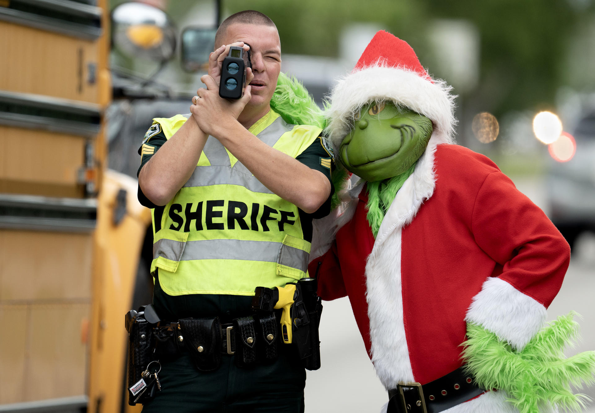 Fotografía cedida por la Oficina de noticias de los Cayos de Florida donde aparece el coronel de la Oficina del Alguacil del Condado de Monroe, Lou Caputo (d), disfrazado del duende 'Grinch', apoyándose en el hombro del sargento James Hager (i), mientras este usa un dispositivo de medición láser para verificar la velocidad de los automovilistas que viajan por la autopista cercana a la escuela primaria Key Largo hoy viernes en Cayo Largo, Florida. EFE/Andy Newman/Florida Keys News Bureau /SOLO USO EDITORIAL /NO VENTAS /SOLO DISPONIBLE PARA ILUSTRAR LA NOTICIA QUE ACOMPAÑA /CRÉDITO OBLIGATORIO
