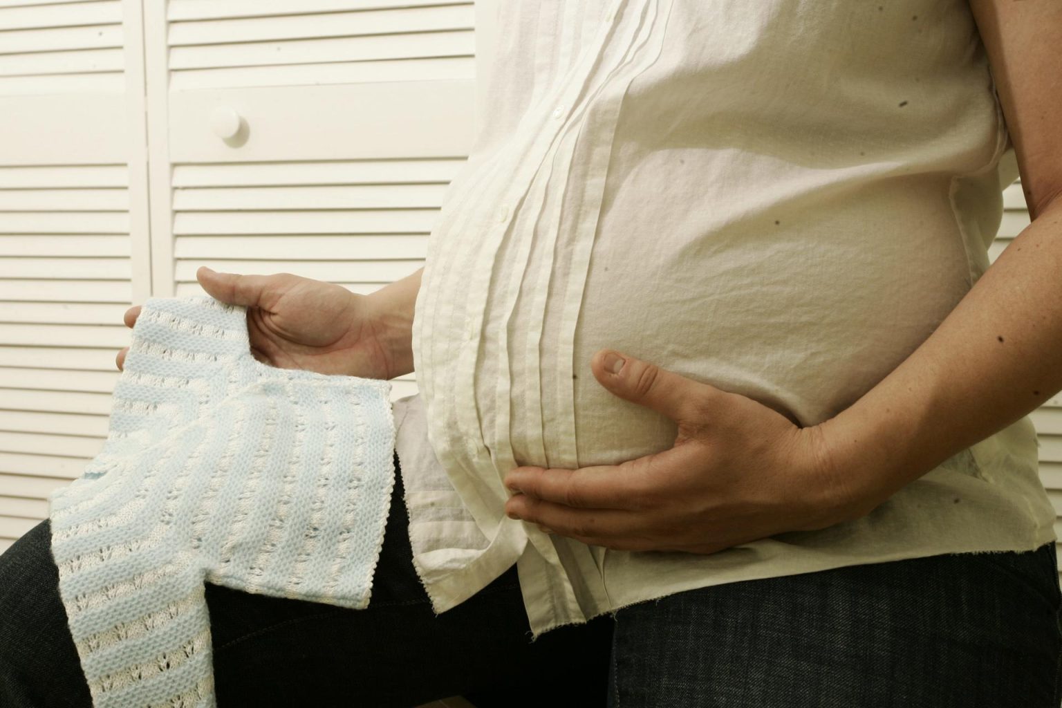 Una mujer en avanzado estado de gestación mira ropa de bebé. Imagen de archivo. EFE/Zayra Mo