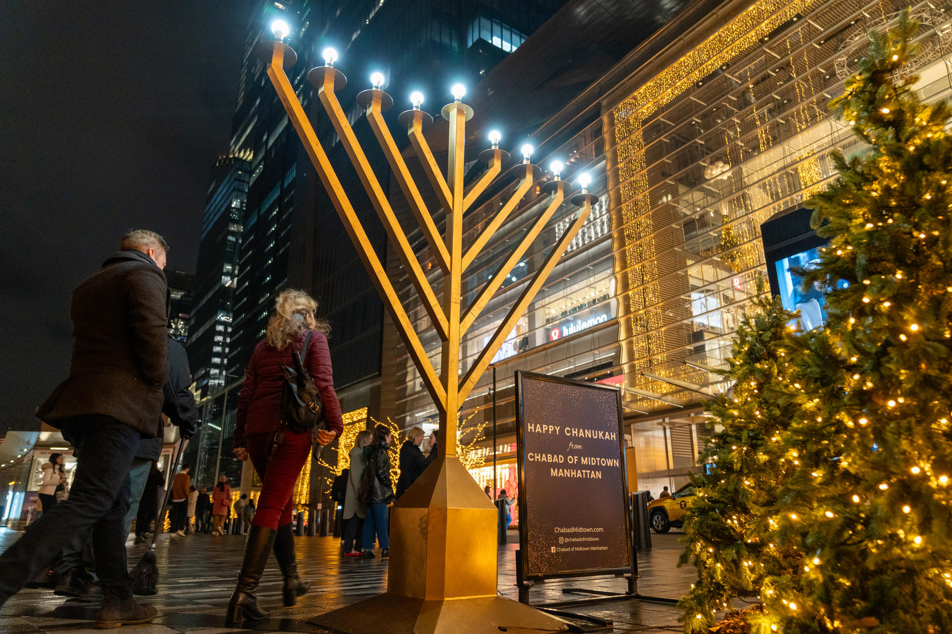 Personas pasan frente a una menorá Judia en la plaza de la estructura del Vessel, punto de atracción construido como parte del Plan de Desarrollo de Hudson Yards, el17 diciembre de 2023, en Nueva York (EE.UU.). EFE/ Angel Colmenares
