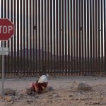 Una mujer intenta mantenerse caliente mientras espera a lo largo del muro fronterizo estadounidense para ser procesada por la Patrulla Fronteriza estadounidense hoy, en Lukeville, Arizona (EE.UU.). EFE/ Allison Dinner