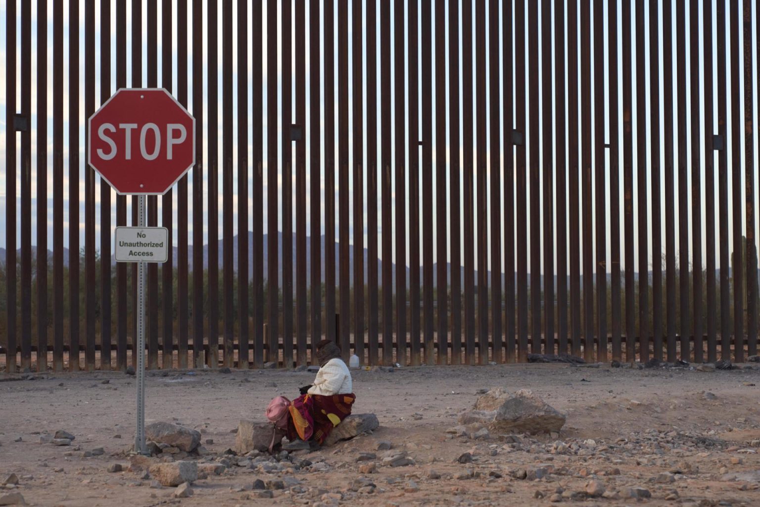 Una mujer intenta mantenerse caliente mientras espera a lo largo del muro fronterizo estadounidense para ser procesada por la Patrulla Fronteriza estadounidense hoy, en Lukeville, Arizona (EE.UU.). EFE/ Allison Dinner