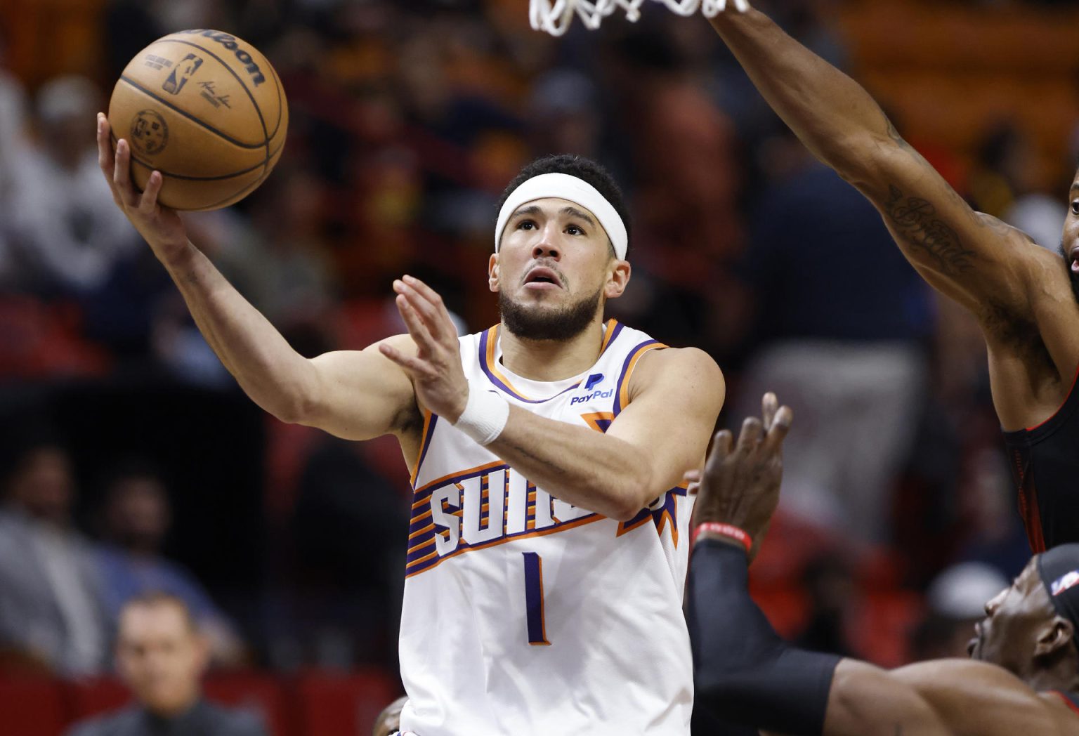 El guardia de los Phoenix Suns, Devin Booker (izq.), dispara alrededor del centro del Miami Heat, Bam Adebayo (der.) hoy, durante la primera mitad del partido de baloncesto de la NBA entre los Miami Heat y los Phoenix Suns en el Kaseya Center de Miami, Florida (EE. UU). EFE/ Rhona Wise