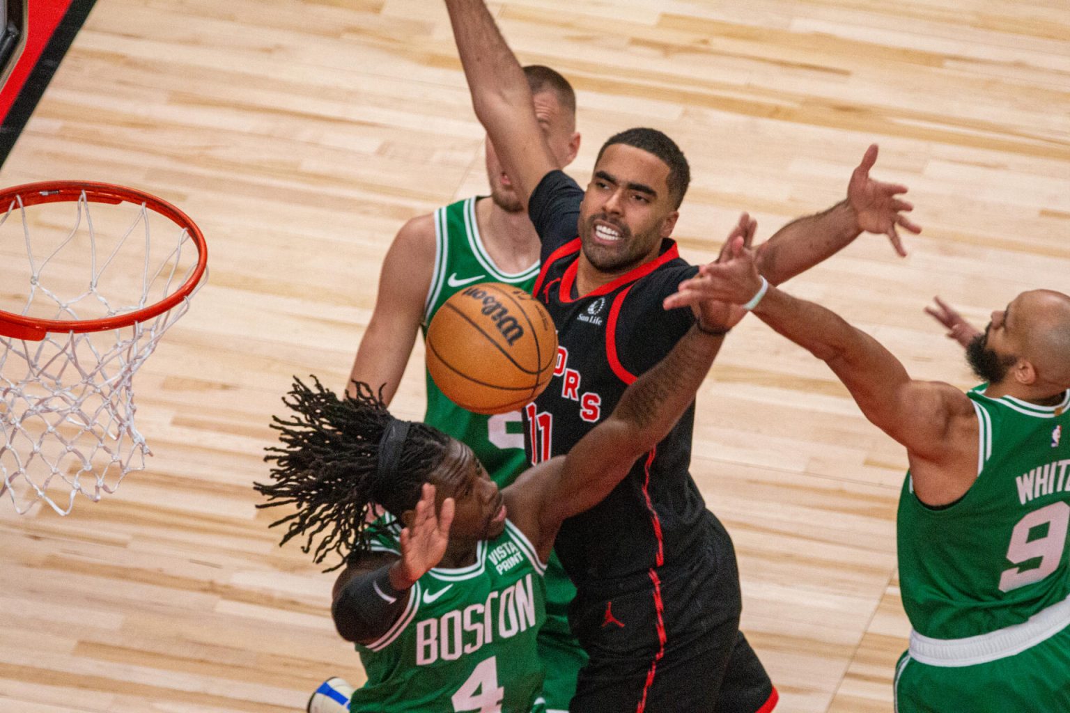 Jontay Porter de los Toronto Raptors rodeado de jugadores de los Boston Celtics True Holiday, Derrick White y Kristaps Porzingis, en acción durante un partido entre los Raptors y los Celtics, hoy en Toronto (Canadá). EFE/Julio César Rivas