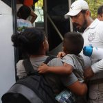 Una migrante con su hijo conversa con un oficial del Instituto Nacional de Migración (INM) antes de abordar un autobús hoy, luego de finalizada una caravana rumbo a Estados Unidos, en el municipio de Mapastepec, estado de Chiapas (México). EFE/ Juan Manuel Blanco