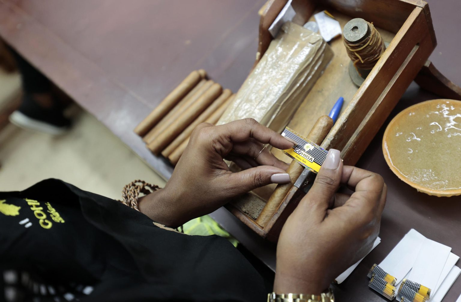 Fotografía de archivo de una trabajadora de la fábrica de tabacos Cohíba mientras etiqueta un habano, en La Habana (Cuba). EFE/Ernesto Mastrascusa