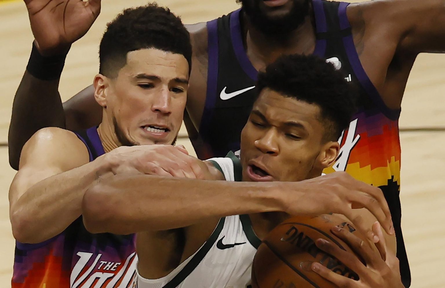 Fotografía de archivo en la que se registró al alero estrella de los Bucks de Milwaukee, Giannis Antetokounmpo (d), al disputar un balón con Devin Booker (i), guardia de los Suns de Phoenix, durante un partido de la NBA, en Phoenix (Arizona, EE.UU.). EFE/Tannen Maury